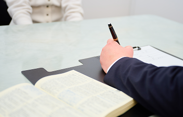 弁護士が相談者の話を聞きながら、メモを取っている様子。