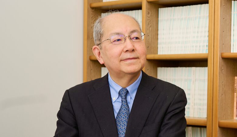 法律書に囲まれた執務室で微笑む弁護士。落ち着いた信頼感を演出。