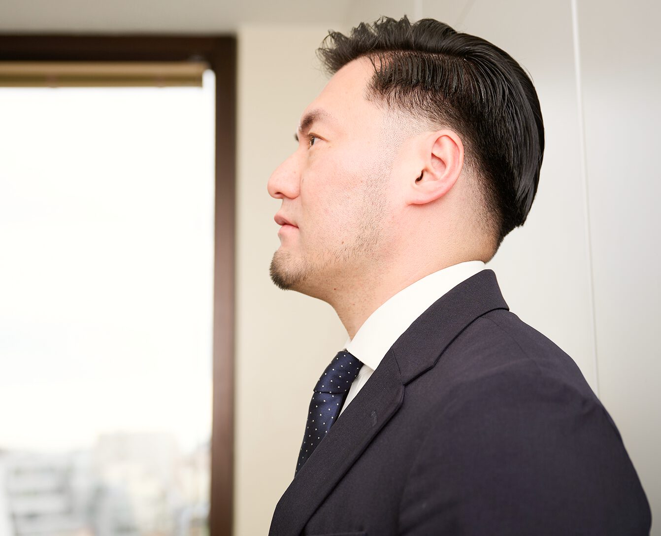 弁護士が窓の外を見つめながら、依頼者の未来を考えている様子。
